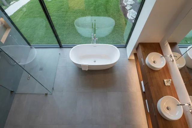 bathroom, bathtub, glass wall, modern design, wooden countertop, double sink, sink, glass shower, garden view, interior lighting, minimalist design, at home, panoramic windows, soothing atmosphere, indoor plants, warm interior, beautiful aesthetics, luxury bathroom, calm atmosphere. Hantverkare till ditt projekt: så anlitar du rätt